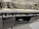 several stainless steel stoves in a commercial kitchen with pots and pans