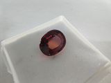a close up of a red garnet stone on a white surface