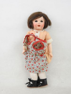 une poupée qui tient un sac et une paire de chaussures