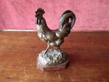 a bronze statue of a rooster on a wooden table