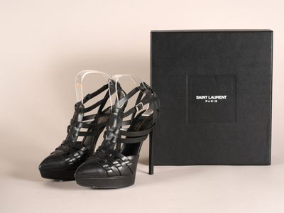 une paire de chaussures noires à talons hauts posée devant une boîte noire