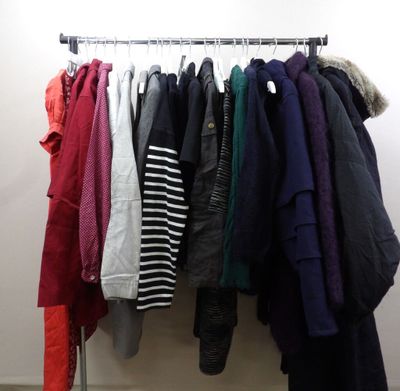 clothes hanging on a rack in a room with white walls