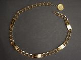 a close up of a gold chain bracelet with a coin on it