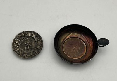 a small coin next to a small cup on a table