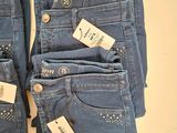 three pairs of blue jeans with tags on them sitting on a table