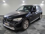La BMW X1 est garée dans le garage, sur un sol à damier.