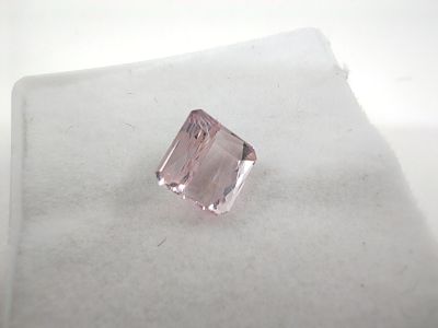 un gros plan d'un diamant rose posé sur une surface blanche