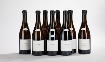 six bottles of wine are lined up in a row on a white surface