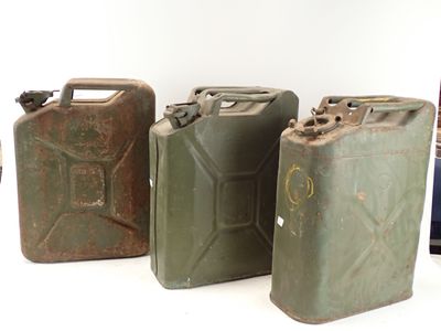 trois jerrycans verts posés les uns à côté des autres sur une surface blanche