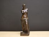 statue en bronze représentant une femme tenant un vase posé sur une table