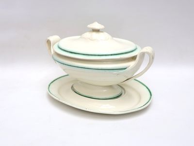 une théière blanche et verte posée sur une soucoupe
