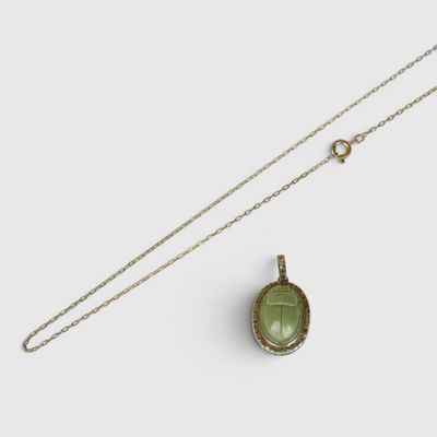 un pendentif en tourmaline verte muni d'une chaîne, sur fond blanc
