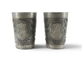pair of silver cups with a crest and coat of arms on them