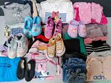 une pile de vêtements et de chaussures pour bébé posée sur une table