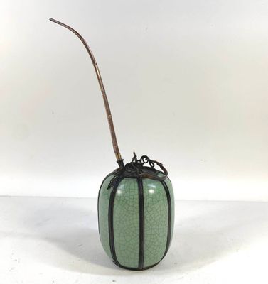 a green vase with a bamboo stick sticking out of it