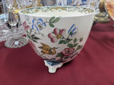 un bol blanc décoré de fleurs et d'oiseaux, posé sur une table