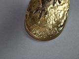 a gold plate with a bird on it on a white surface