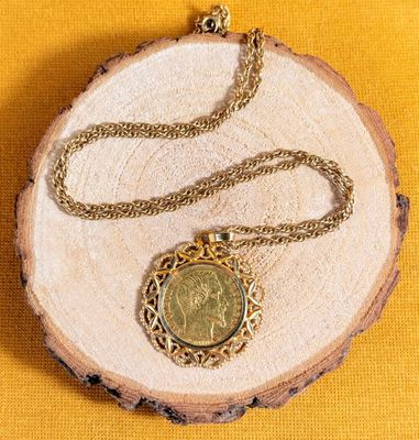collier composé d'une chaîne en or et d'une pièce de monnaie sur fond jaune