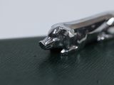 a silver dog figurine sitting on top of a green table