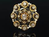 un gros plan d'une bague ornée de perles et d'or sur un fond noir
