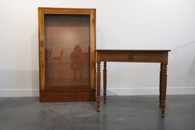 une petite table sur laquelle est posé un miroir, à côté d'une autre petite table avec une chaise