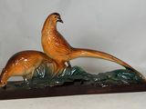 une figurine représentant un faisan et un faisanau, posée sur un socle en bois