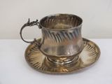 a silver cup and saucer sitting on a saucer