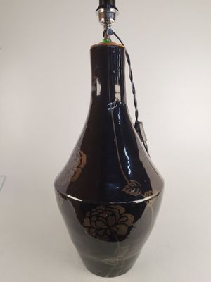 un vase noir orné de motifs dorés, posé sur une table