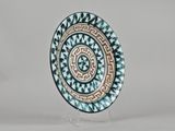 a close up of a decorative plate on a stand on a white surface