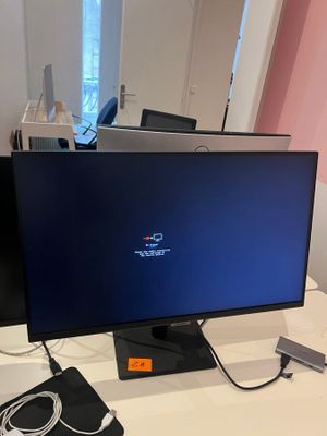 a computer monitor sitting on a desk with a charger