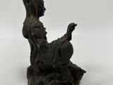 statue of a woman sitting on a rock holding a cell phone