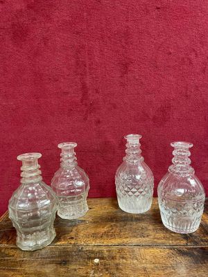 quatre vases en verre transparent posés sur une table en bois