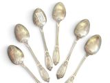 six silver spoons are arranged in a circle on a white surface