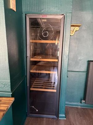 a wine cooler in the corner of a room with green walls