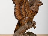 une photo représentant une statue en bois d'un oiseau posé sur une souche d'arbre