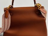 the small brown handbag is sitting on a white surface