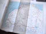 un livre ouvert, sur lequel figure une carte, posé sur une table