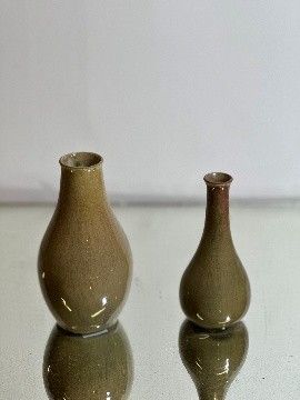 two small vases sitting on a table next to each other
