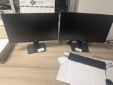 two computer monitors sitting on top of a wooden desk next to a keyboard