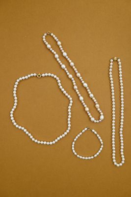 a white bead necklace and a pair of scissors on a brown surface