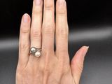 woman ' s hand with a pearl ring on it ' s finger
