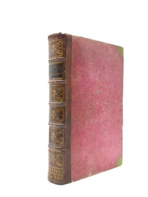 un vieux livre à la couverture rose posé sur une surface blanche