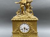 a gold clock with a statue on top of it