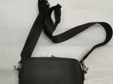 a black purse with a black strap on a bed