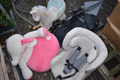 trois peluches posées par terre à côté d'un siège auto pour bébé
