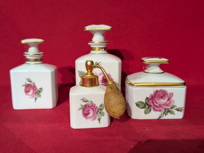 trois petites bouteilles ornées de fleurs, posées sur un fond rouge