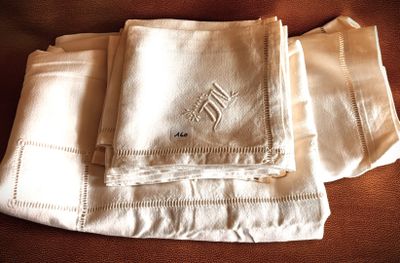 three white linen napkins with embroidered monograms on them on a couch
