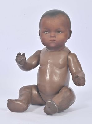 a small baby doll sitting on the floor with its hands in the air