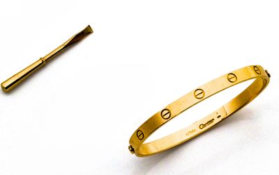 un bracelet en or et une broche sur un fond blanc