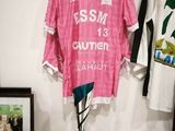 une chemise rose accrochée au mur à côté d'un ballon de basket